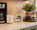 Kitchen counter with coffee maker, mug, photo frame, and jars.